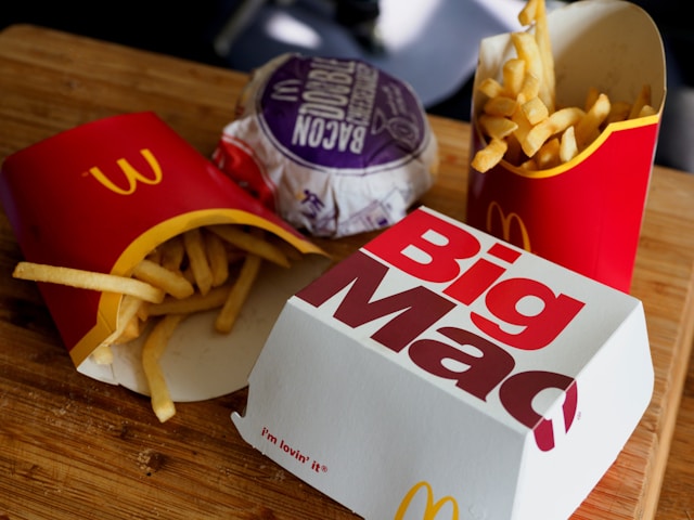 木のテーブルにマックのハンバーガーが2種類、ポテト2つが置いてある画像