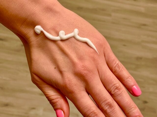 ピンクのネイルの手の甲にクリームがついている画像