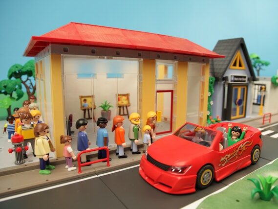 おもちゃのレゴで、お店、赤いオープンカーに乗った人、人の行列が作ってある画像