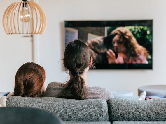 家のテレビをソファに座って親子で観ている後姿の画像