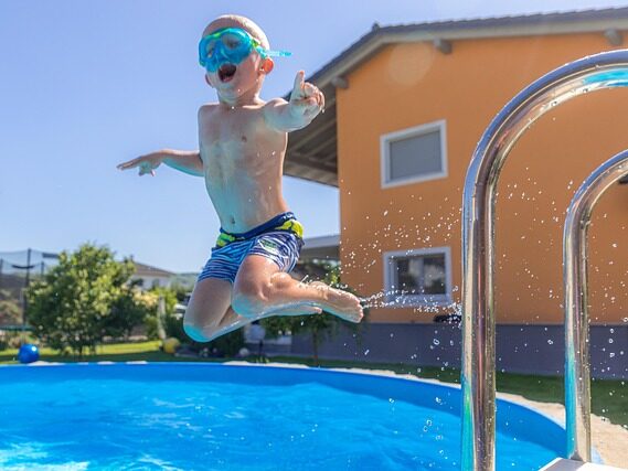 水中眼鏡をかけた子どもが プールの上でジャンプしている画像