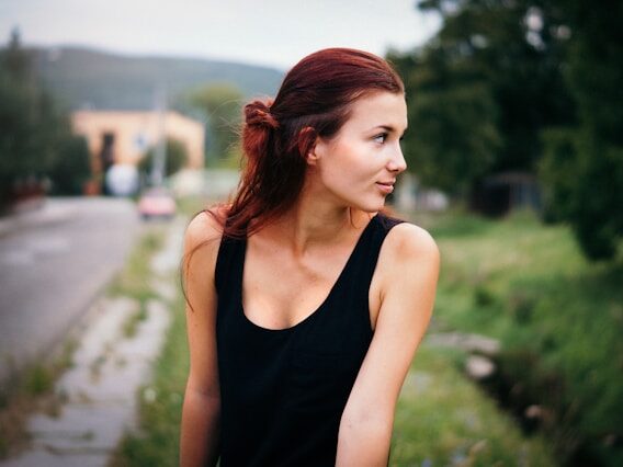 黒いタンクトップを着ているロングヘアーの女性が、外にいる画像