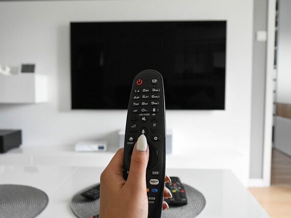テレビのリモコンをテレビに向けている画像