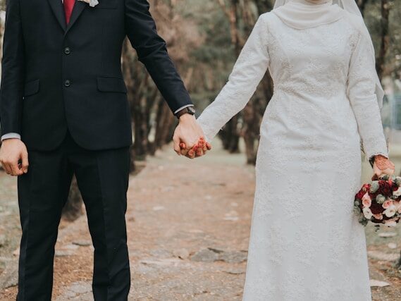 ウエディング衣装を着た男女が、屋外で手をつないでいる首から下の画像