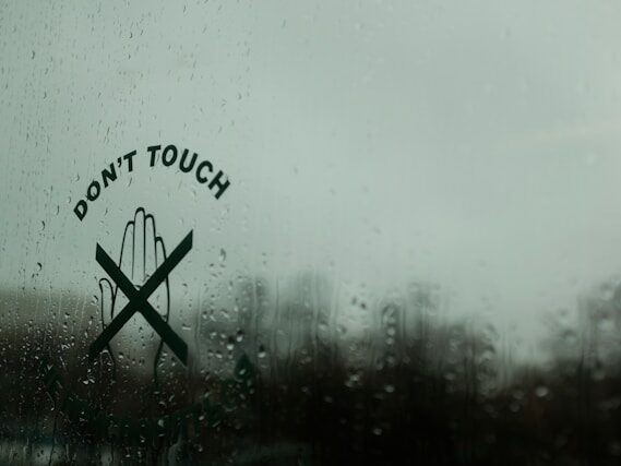 don't touchと書いてある窓が雨でぬれている画像