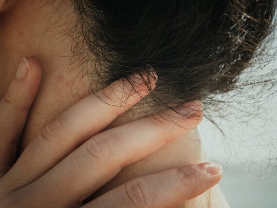 女性が耳の下、首あたりを押さえている画像