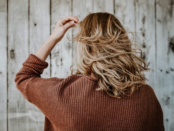 女性が髪をかき上げようとしている後姿の画像