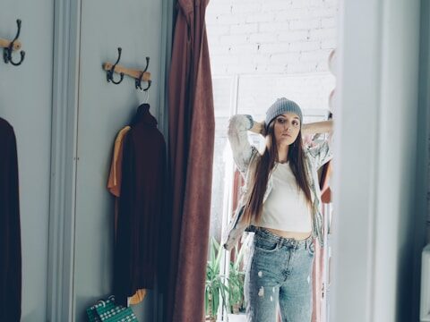 女性が鏡でコーディネートをチェックしている画像