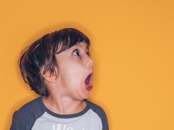 黄色い背景で、男の子がびっくりした様子で口を開けている画像
