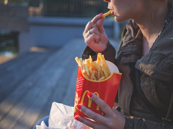女性が外でマクドナルドのポテトを食べている画像