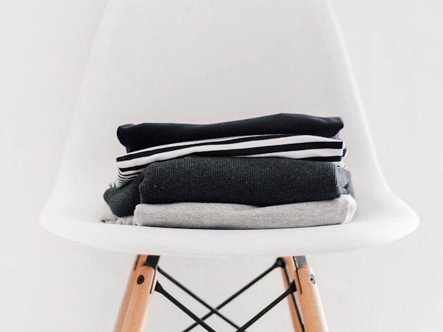 白い椅子の上に畳んだ洋服がある画像