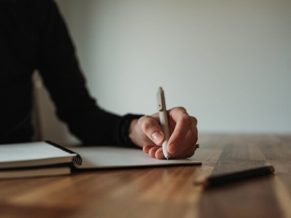 女性がノートにペンで書いている画像