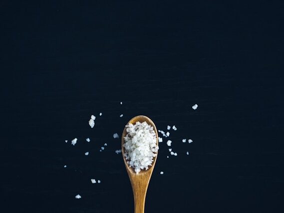 黒い背景に気のスプーンい塩が盛ってある画像