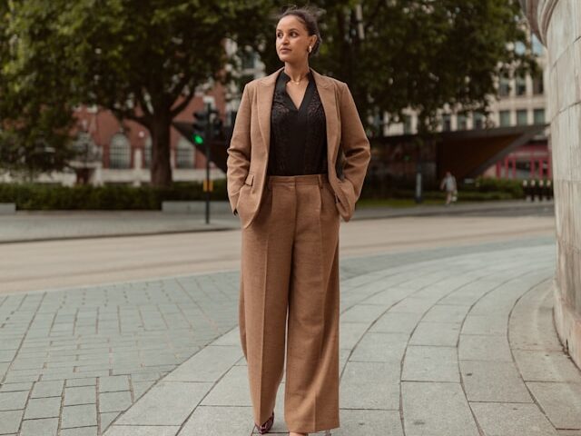 茶色いスーツを着た女性が外で立っている画像