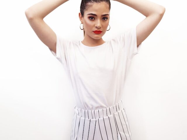 白い服を着た女性が両手を頭の後ろに置いて立っている画像