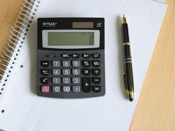 ノートの上に電卓とペンが置いてある画像