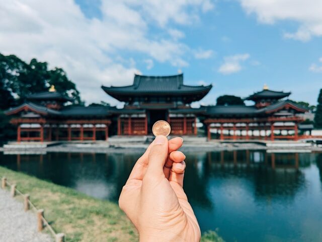 左手で10円をもって建物と比べている画像