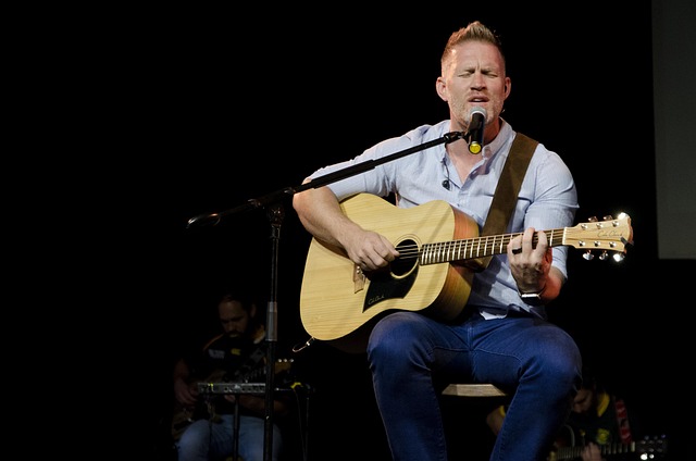 男性がギターを抱えて歌っている画像