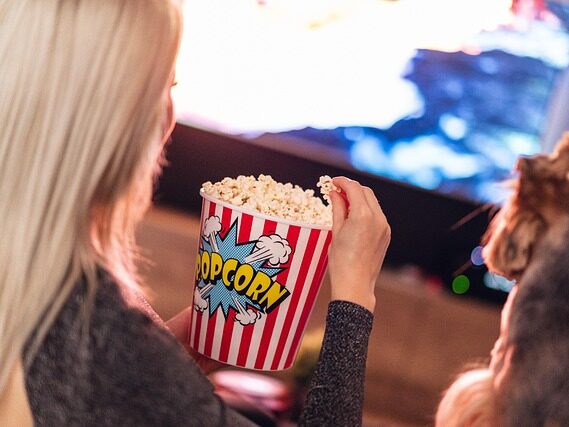女性がポップコーンを食べながらテレビを観ている画像