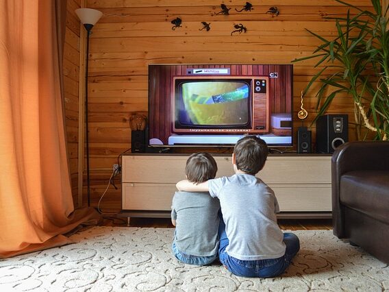 兄弟が肩を組んで座ってテレビを観ている画像