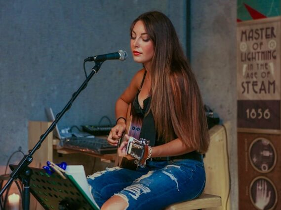 女性がギターを弾き語りしている画像