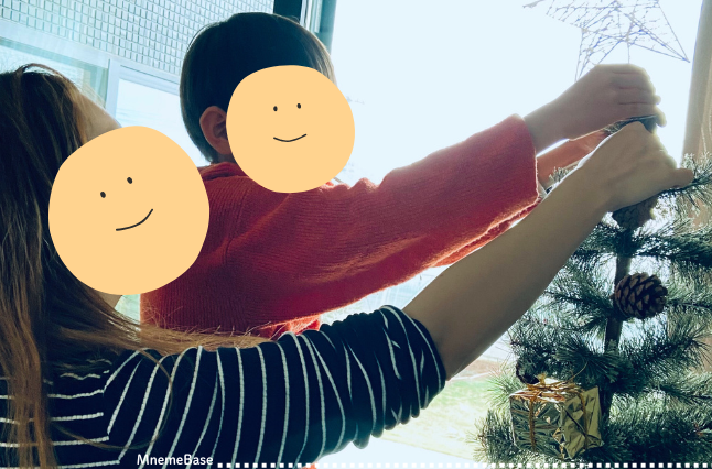 クリスマスツリーに親子で飾り付けている画像