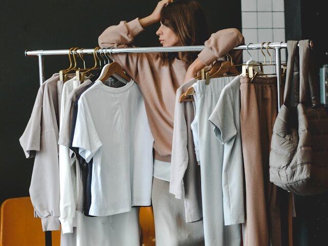 女性が洋服がかかっているラックに寄りかかっている画像