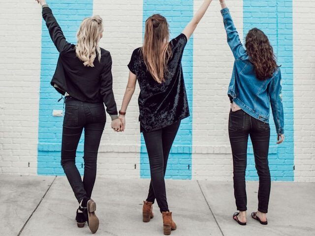 手をつないで歩く3人の女性の画像