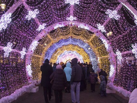 イルミネーションのトンネルを沢山の人が通っている画像