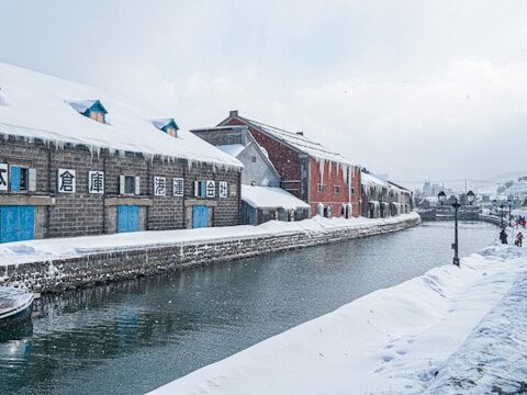 茶色のコンクリートの建物の近くで水上に浮かぶ白いボートの画像
