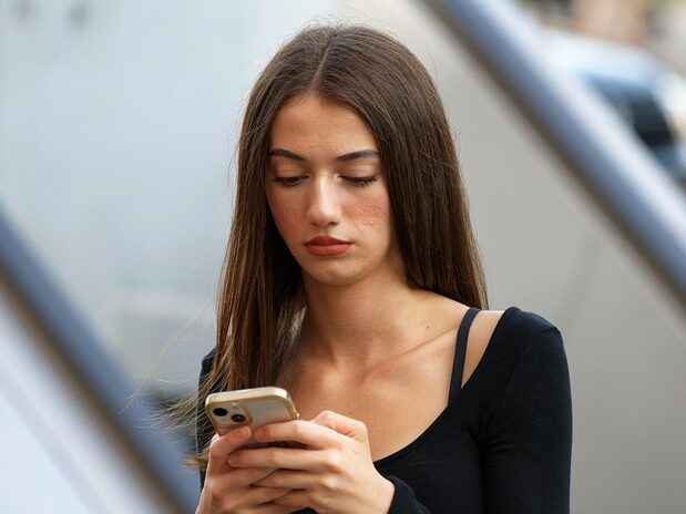 長い髪の女性が携帯を見ている画像