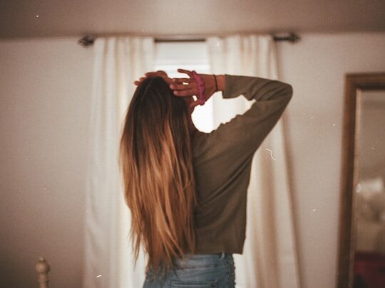 部屋にいる髪の長い女性の後姿の画像