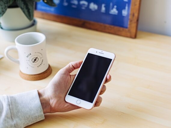 マグカップが置いてあるテーブルで携帯電話を持っている画像