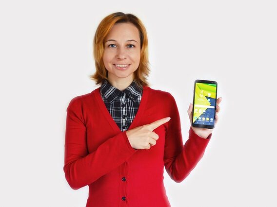 赤い服を着た女性が携帯を指さしている画像