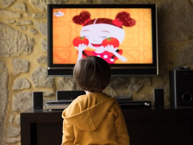 男の子が立ってテレビを観ている画像