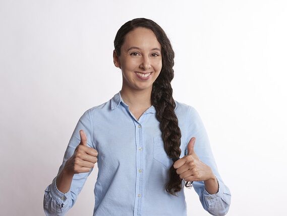 長い三つ編みの女性が両手でグッドサインをしている画像
