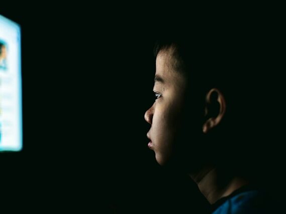 暗闇で子どもがテレビを観ている画像