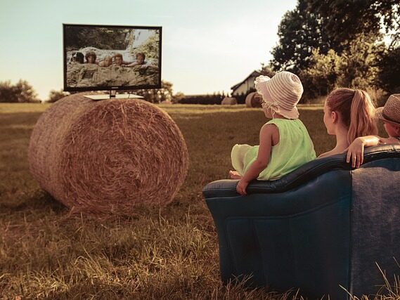 外のソファに座って子どもたちがテレビを観ている画像
