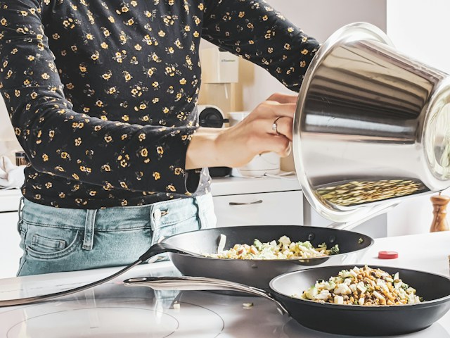 女性が料理を皿に分けている画像
