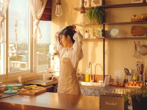 女性がキッチンで髪をまとめている画像