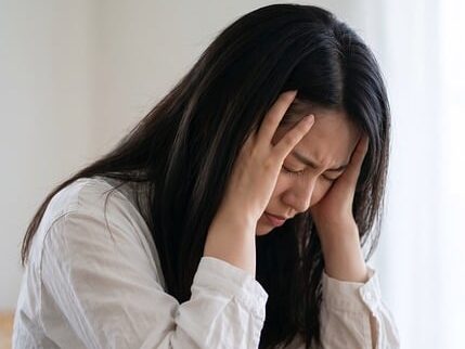 頭を抱えている髪の長い女性の画像