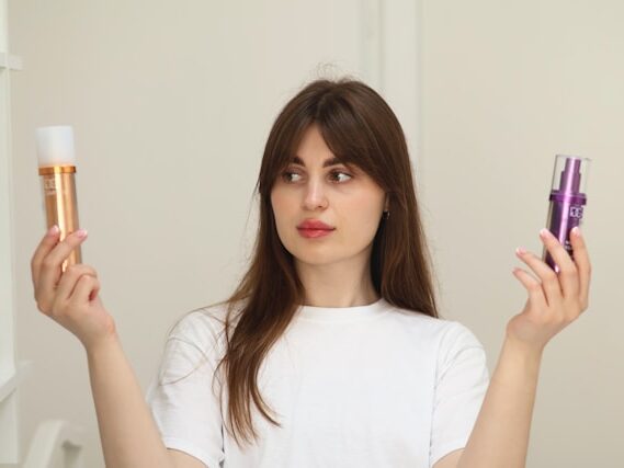 髪の長い女性が両手にヘアケアアイテムを持っている画像