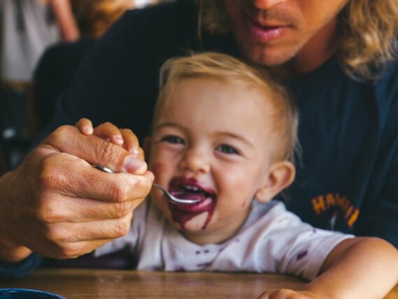 赤ちゃんがスプーンで食べさせてもらっている画像