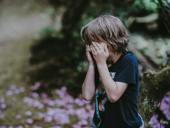 男の子が両手で顔を覆っている画像