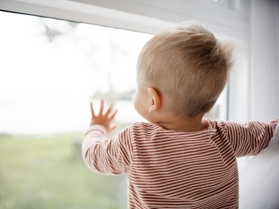 子どもが窓に手を当てている画像