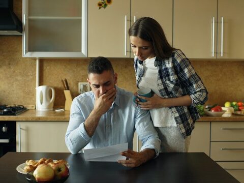 夫婦が真剣な顔で紙を読んでいる画像