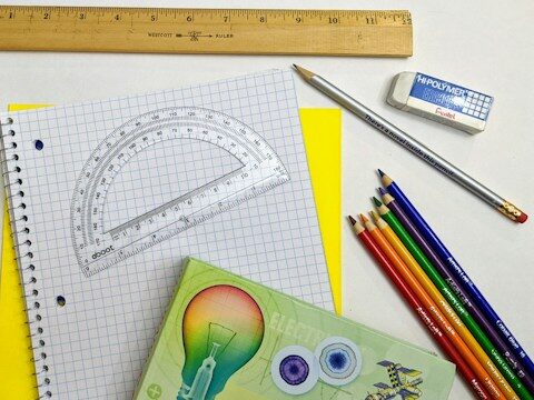 ノート、分度器、色鉛筆などの文房具が置いてある画像