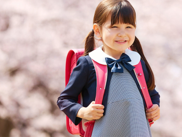 女の子が外でピンクのランドセルを背負っている画像