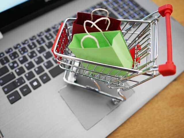 パソコンのキーボードに紙袋が入った小さなショッピングカートが置いてある画像